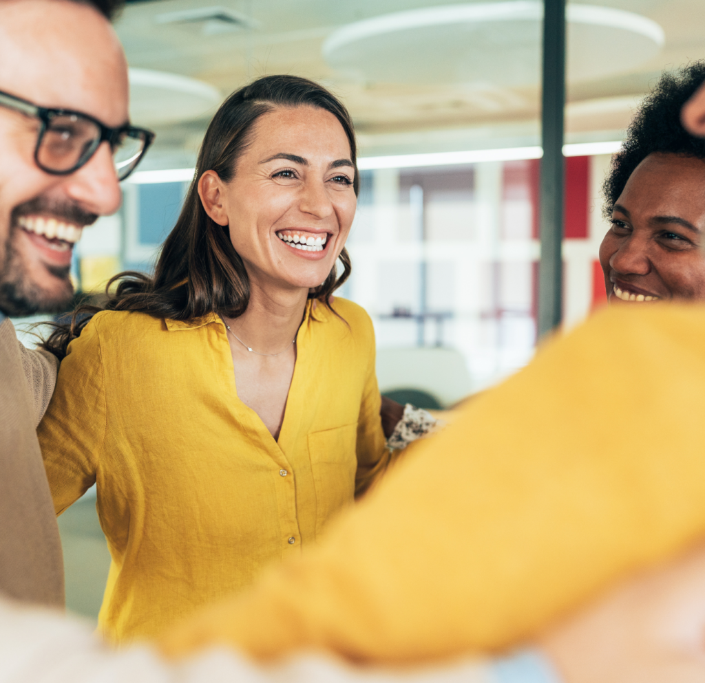 Smiling team members standing in a circle, celebrating unity and a positive work environment.