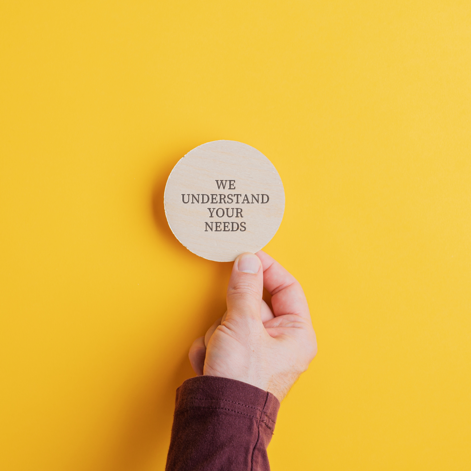 Hand holding a wooden badge with text 'We Understand Your Needs' – representing personalised, flexible HR support.