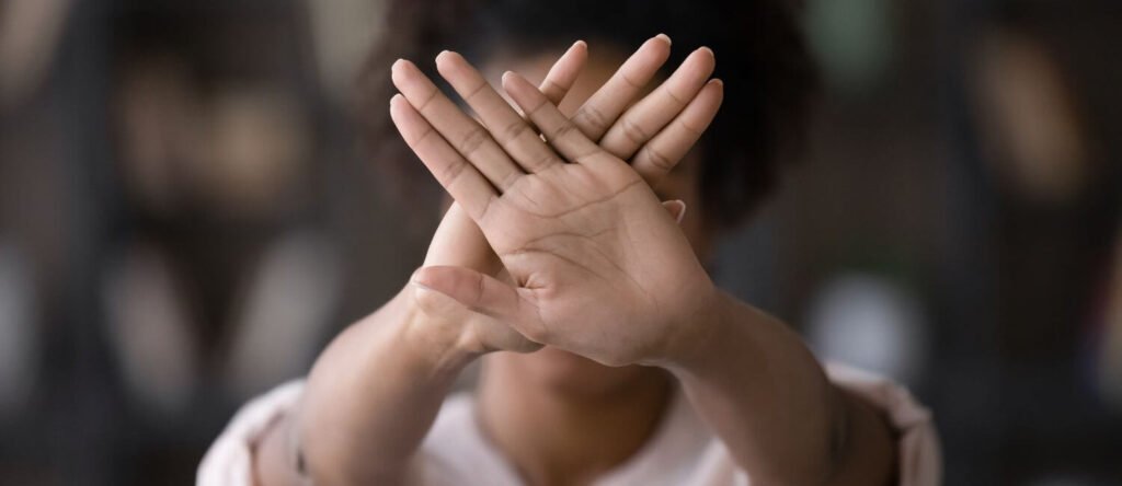 Individual crossing hands to indicate no tolerance for workplace harassment