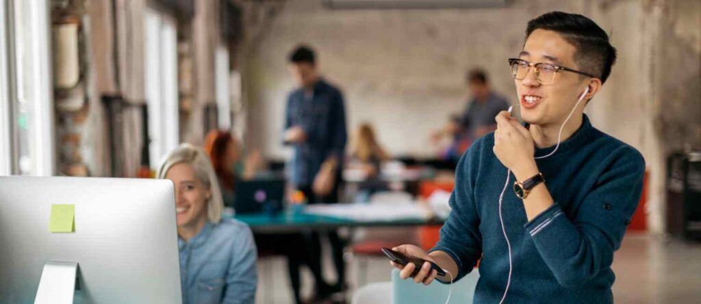 Young employee smiling while speaking, with manager observing supportively in a modern office setting.