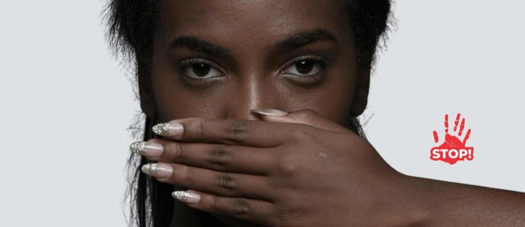 A woman covers her mouth with her hand, symbolizing forced silence. A red handprint with the word “STOP!” appears beside her, representing the fight against workplace harassment and the silencing of victims.