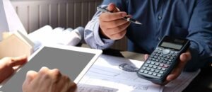 An employer sitting at a cluttered desk, looking overwhelmed while holding paperwork — representing the stress and financial consequences of missing HR documentation.