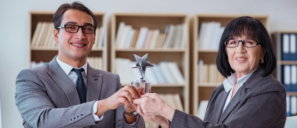 Smiling employees in an office celebrating a recognition award for outstanding performance on a limited budget.