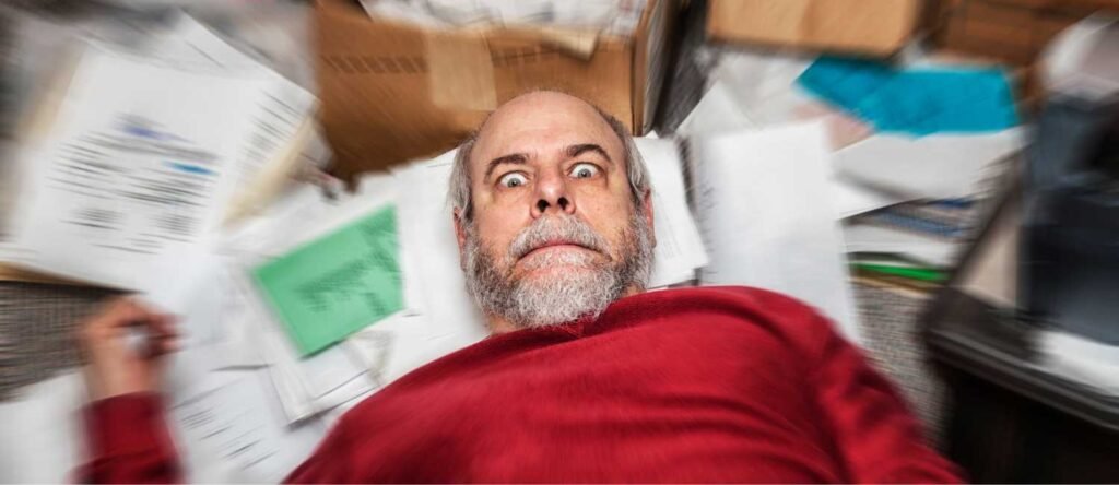 Stressed business owner overwhelmed by paperwork and HR documents highlighting risks of poor HR management in UK SMEs