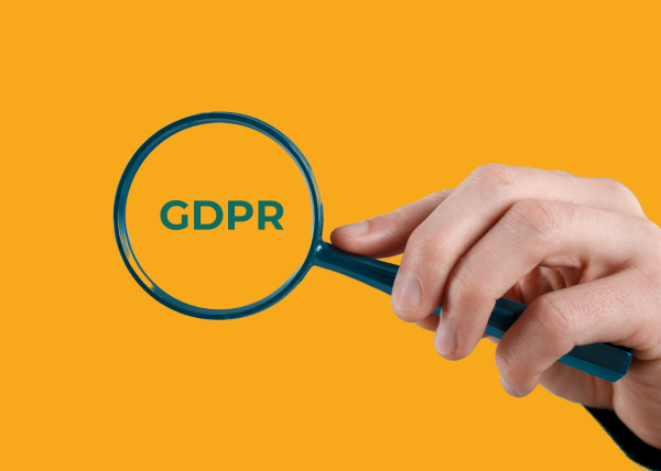 Magnifying glass over the word GDPR – symbolising data protection and compliance scrutiny.